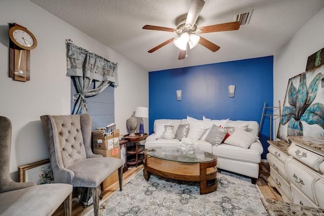 interior space with light wood finished floors, ceiling fan, visible vents, and a textured ceiling