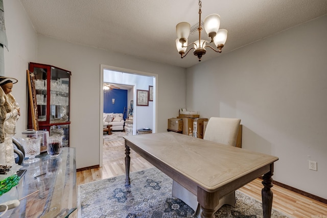 office space featuring a textured ceiling, light wood-type flooring, a chandelier, and baseboards