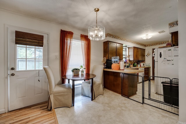 kitchen with a notable chandelier, light countertops, hanging light fixtures, freestanding refrigerator, and a textured ceiling