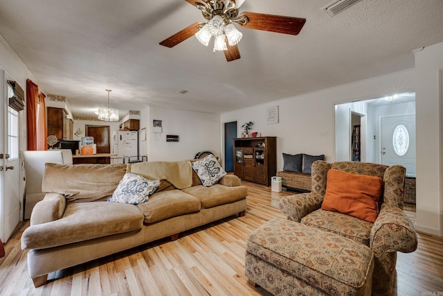 living room featuring a textured ceiling, light wood-style flooring, ceiling fan with notable chandelier, and visible vents