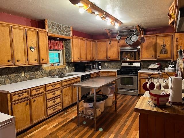 kitchen with appliances with stainless steel finishes, a textured ceiling, dark hardwood / wood-style flooring, and backsplash