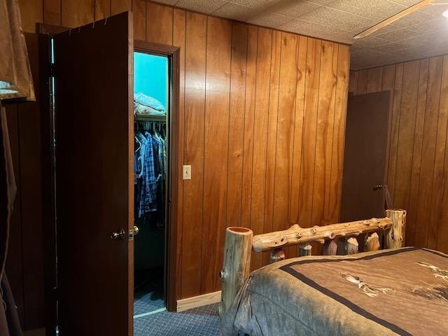 carpeted bedroom with wood walls and a closet