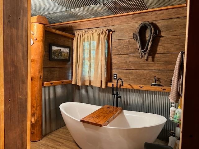 bathroom featuring wood walls, a tub, and hardwood / wood-style flooring