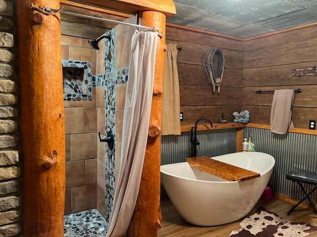 bathroom featuring wood walls, wood-type flooring, and curtained shower