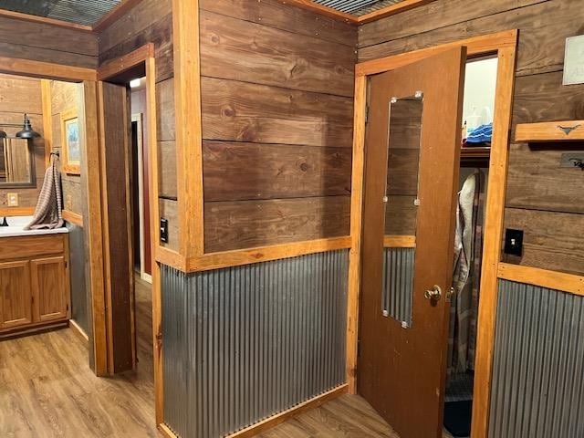 doorway featuring light wood-type flooring and wooden walls