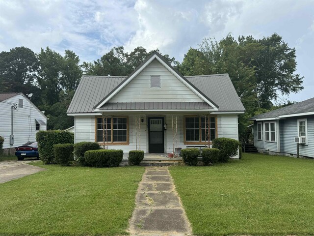 bungalow-style home featuring covered porch, cooling unit, and a front lawn