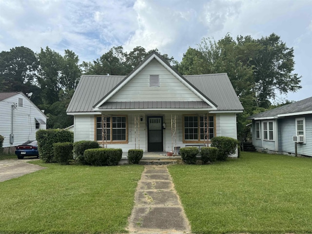 bungalow-style home featuring metal roof, a porch, a front lawn, and cooling unit