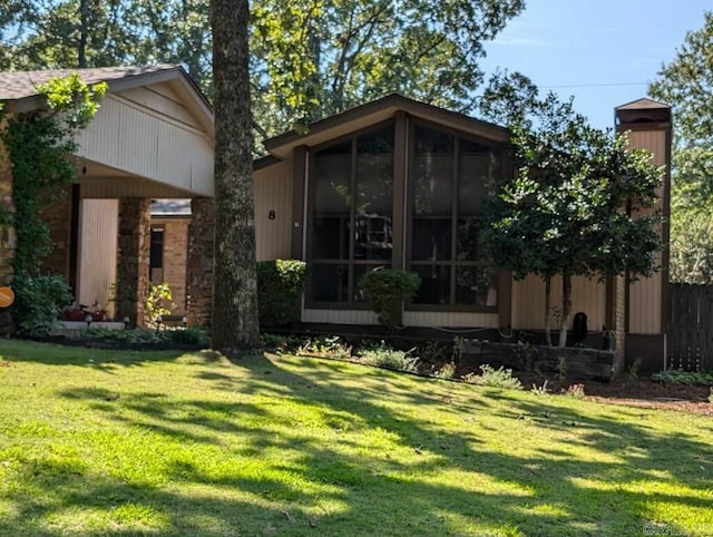 back of house with a sunroom and a lawn