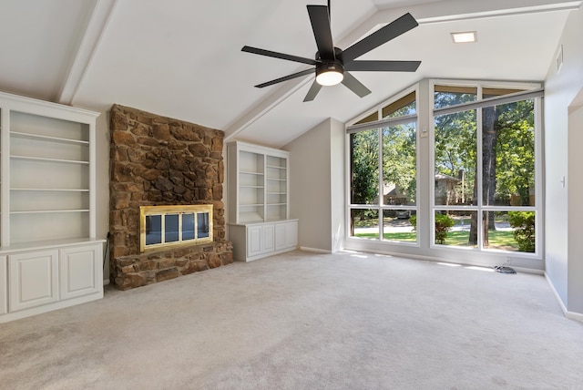 unfurnished living room with ceiling fan, lofted ceiling with beams, a stone fireplace, and carpet flooring