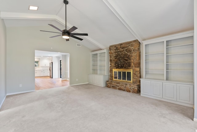 unfurnished living room featuring built in shelves, a fireplace, lofted ceiling with beams, light carpet, and ceiling fan