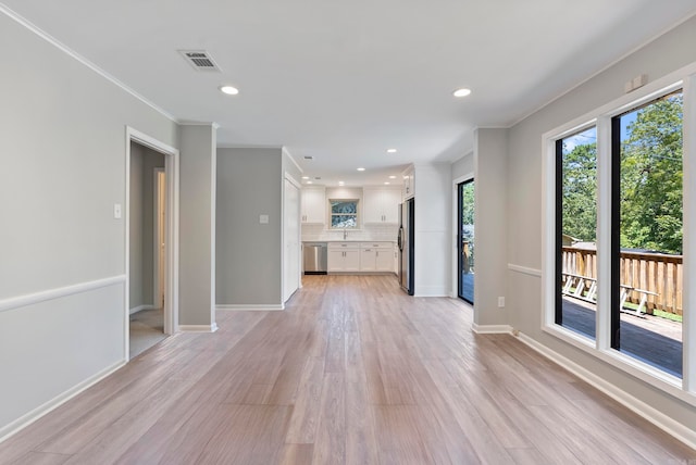 unfurnished living room with crown molding and light hardwood / wood-style floors