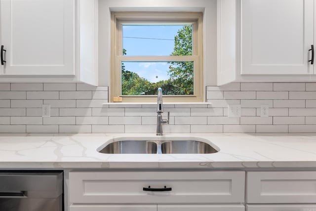 kitchen with sink, tasteful backsplash, light stone countertops, and white cabinets