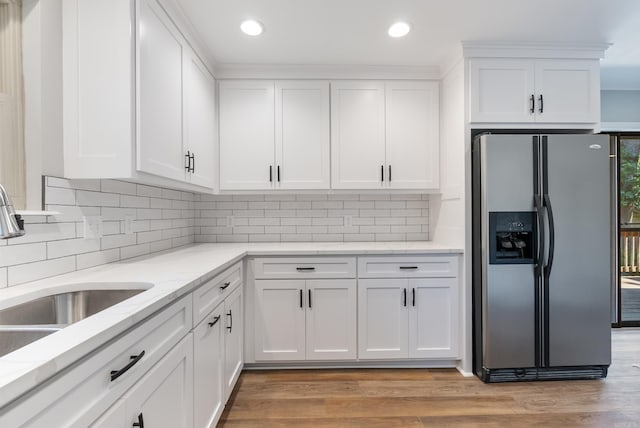 kitchen featuring white cabinetry, stainless steel fridge with ice dispenser, light hardwood / wood-style floors, and tasteful backsplash