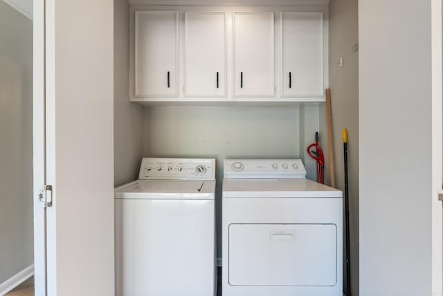 washroom featuring washing machine and dryer, cabinets, and hardwood / wood-style floors