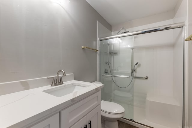 bathroom with a shower with door, vanity, and toilet