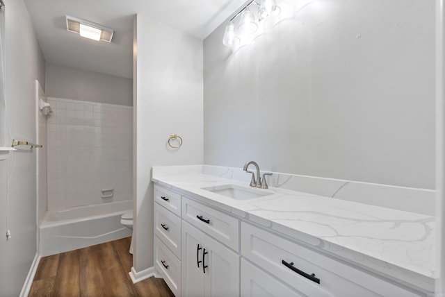 full bathroom featuring toilet, tiled shower / bath, vanity, and wood-type flooring