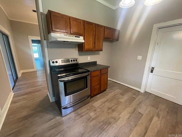 kitchen with under cabinet range hood, wood finished floors, stainless steel electric range, brown cabinetry, and dark countertops