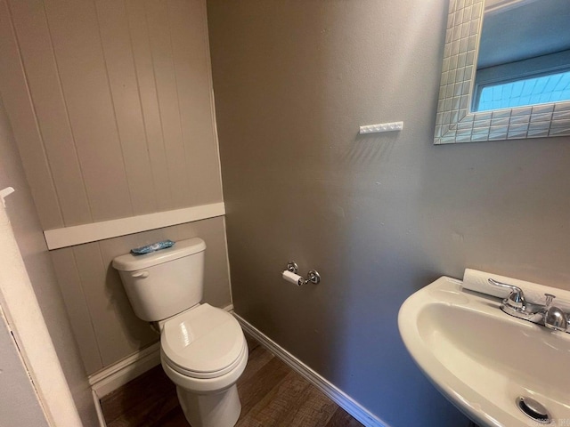 bathroom with wood finished floors, a sink, toilet, and baseboards