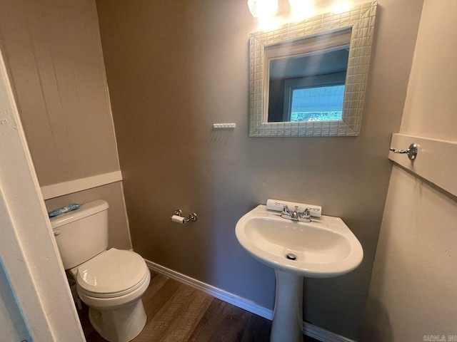 half bath featuring toilet, baseboards, and wood finished floors