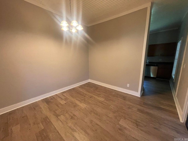 unfurnished room featuring dark wood-style flooring, an inviting chandelier, and baseboards