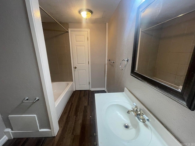 bathroom featuring a textured ceiling, tiled shower / bath, vanity, and wood-type flooring