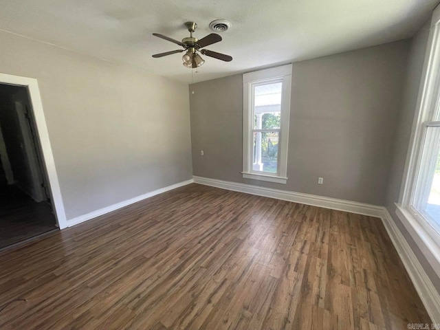 empty room featuring visible vents, dark wood finished floors, baseboards, and ceiling fan