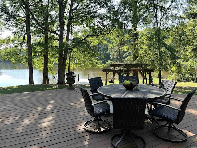 deck with outdoor dining space and a water view