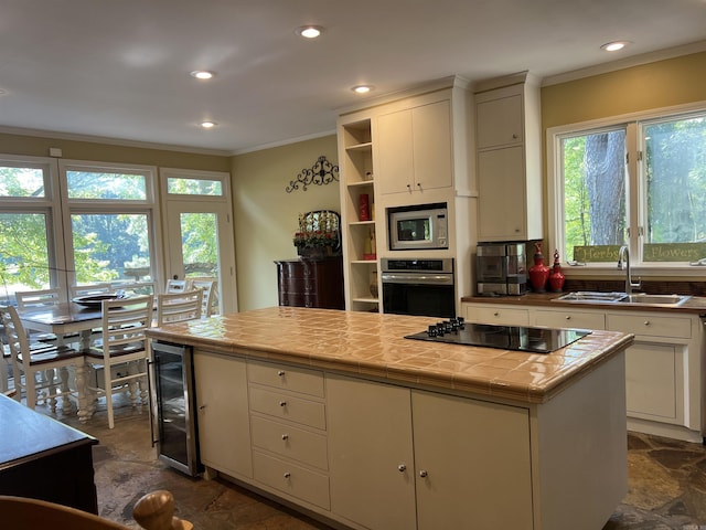 kitchen with wine cooler, black electric stovetop, a sink, built in microwave, and oven