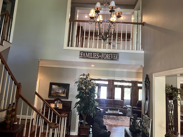 foyer featuring a notable chandelier, stairway, a high ceiling, ornamental molding, and wood finished floors