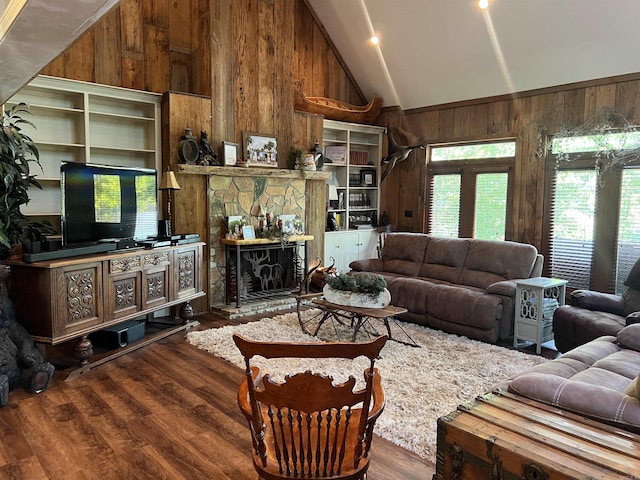 living area with high vaulted ceiling, a stone fireplace, wood finished floors, and wooden walls