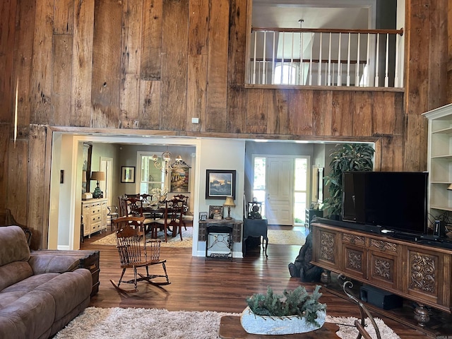 living room with a high ceiling, wood finished floors, and wooden walls