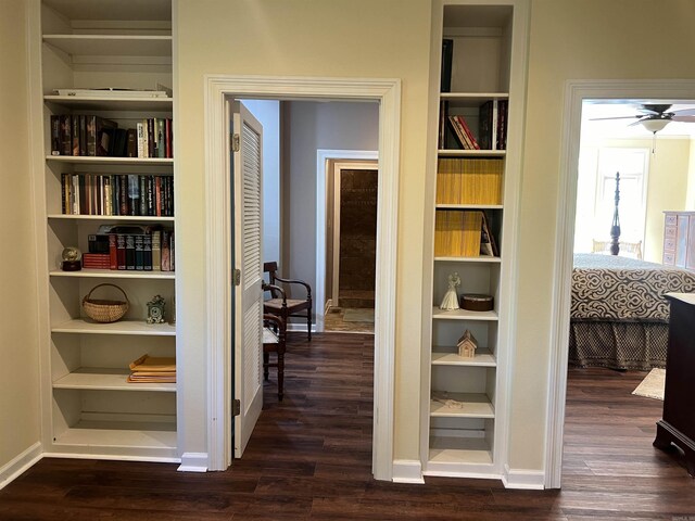 hallway featuring built in features, baseboards, and dark wood-style flooring