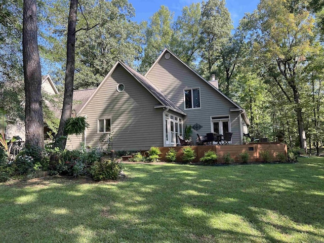 rear view of property featuring a deck, a yard, and a chimney