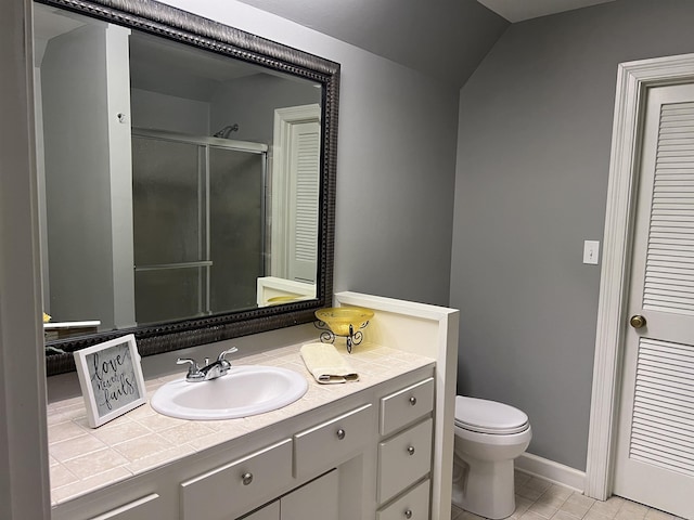 bathroom featuring tile patterned flooring, toilet, vanity, baseboards, and a stall shower