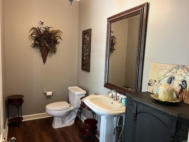 bathroom with toilet, baseboards, and wood finished floors