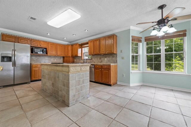 kitchen featuring ceiling fan, a kitchen island, tasteful backsplash, light tile patterned floors, and stainless steel appliances