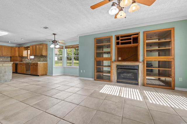 unfurnished living room featuring ceiling fan, ornamental molding, light tile patterned floors, and a tile fireplace