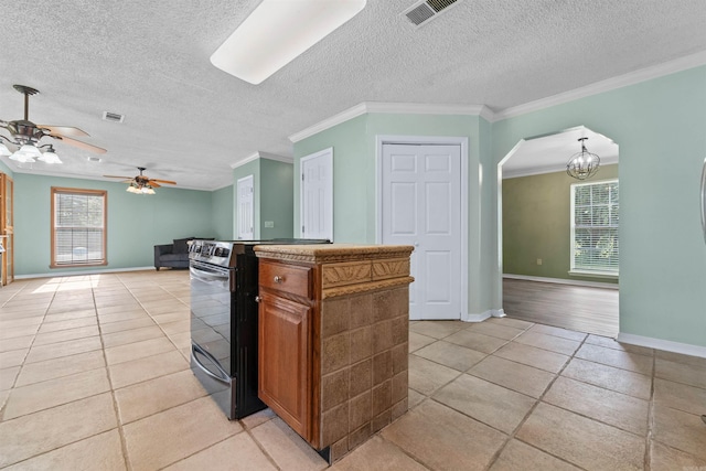 kitchen featuring a wealth of natural light, light tile patterned flooring, ornamental molding, and a textured ceiling