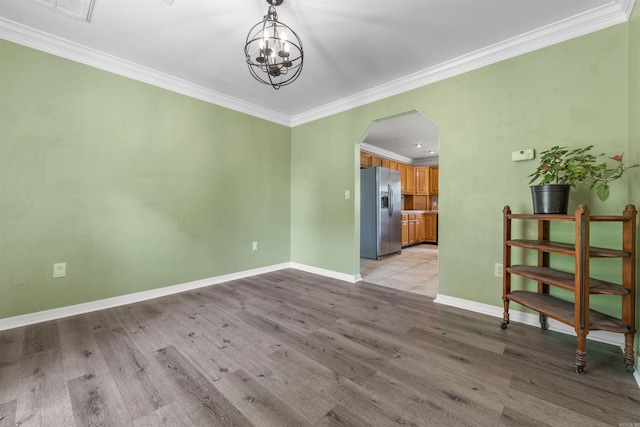 empty room featuring crown molding, light hardwood / wood-style floors, and a chandelier