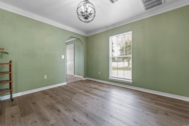 empty room featuring hardwood / wood-style flooring, ornamental molding, and a chandelier