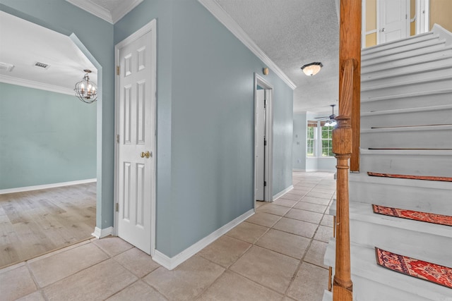 hallway with a textured ceiling, a notable chandelier, crown molding, and light tile patterned floors