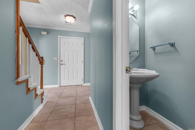 bathroom with ornamental molding, tile patterned flooring, a textured ceiling, and baseboards