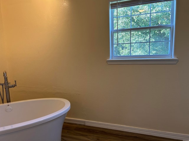 bathroom with a bath, hardwood / wood-style flooring, and a healthy amount of sunlight