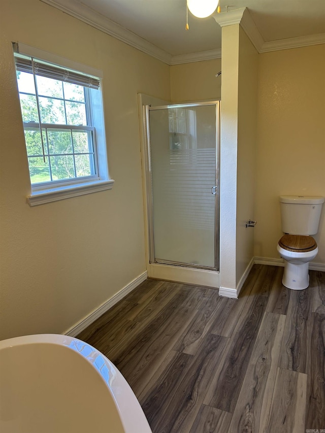 bathroom with crown molding, toilet, a stall shower, wood finished floors, and baseboards