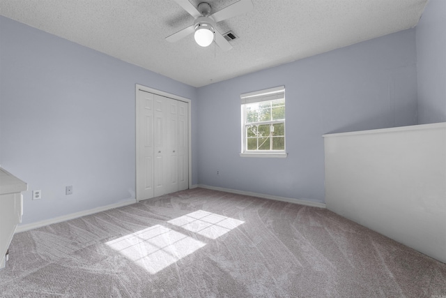 unfurnished bedroom with ceiling fan, light colored carpet, a closet, and a textured ceiling