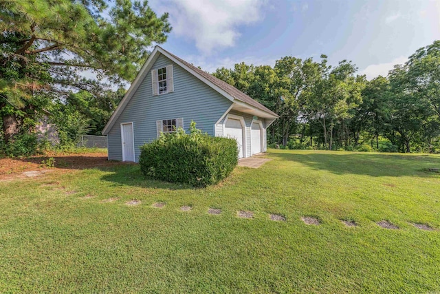 view of property exterior featuring a garage, a yard, and an outbuilding