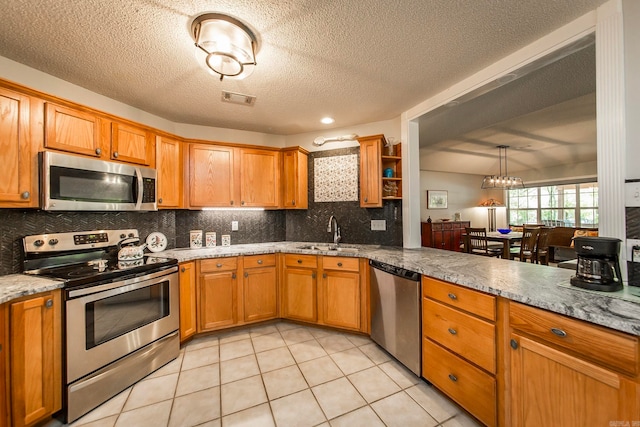 kitchen with appliances with stainless steel finishes, decorative backsplash, sink, a textured ceiling, and light tile patterned floors