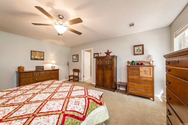 bedroom with ceiling fan, light carpet, and a textured ceiling