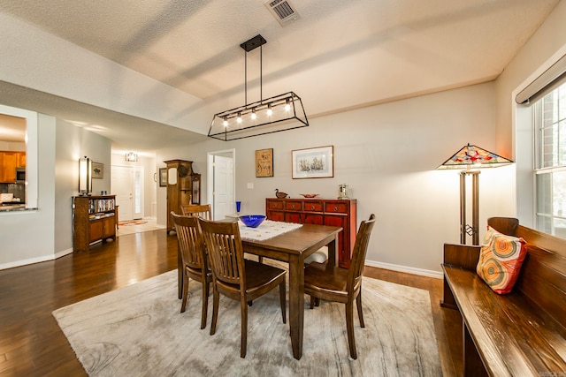 dining area with dark hardwood / wood-style floors, a notable chandelier, and a textured ceiling