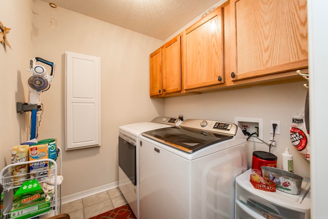 clothes washing area featuring light tile patterned floors, washer and clothes dryer, a textured ceiling, and cabinets